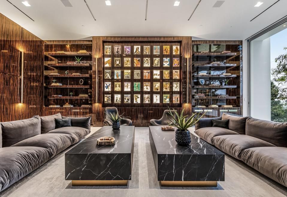 Interior lounge at The One in Bel Air with book-matched wood paneling, illuminated display shelving, and stone tables